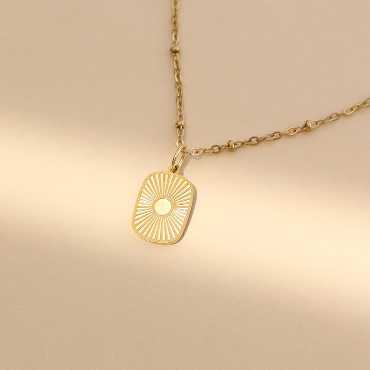 Gold rectangular sunburst medallion pendant on a dainty chain