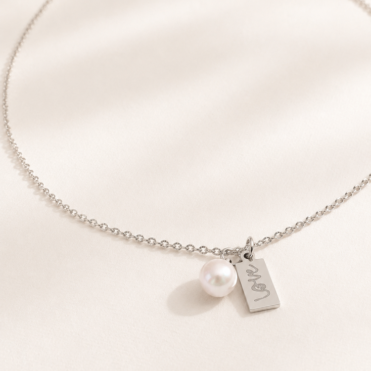 Silver necklace with a pearl and 'I love you' tag on a white background
