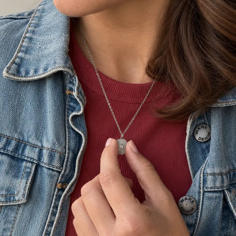 Woman in a denim jacket holding her engraved handwriting medallion necklace
