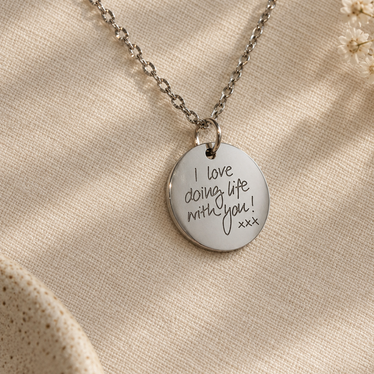 Silver disc pendant engraved with the handwritten message 'I love doing life with you xxx'