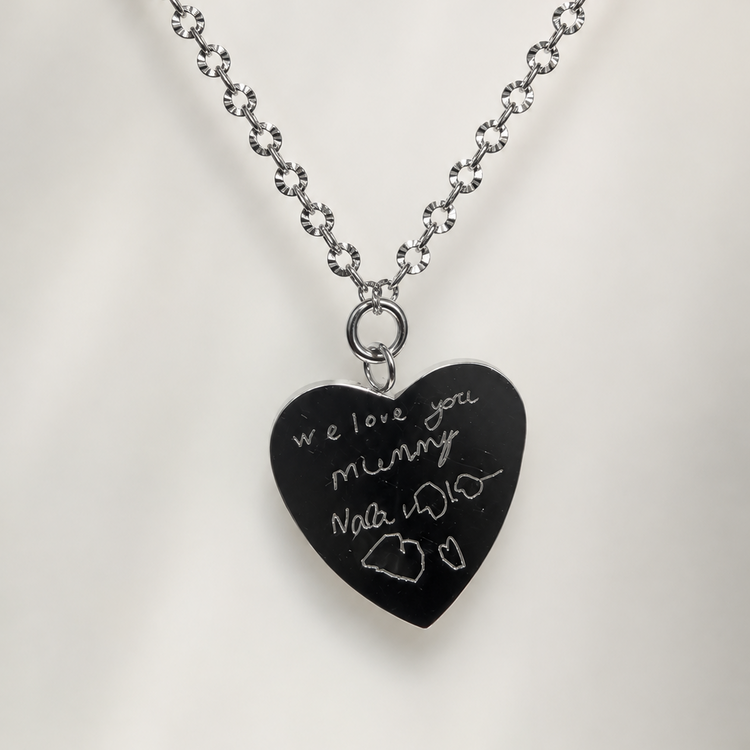 Heart pendant engraved with a child's handwriting 'we love you mummy' and a small drawing