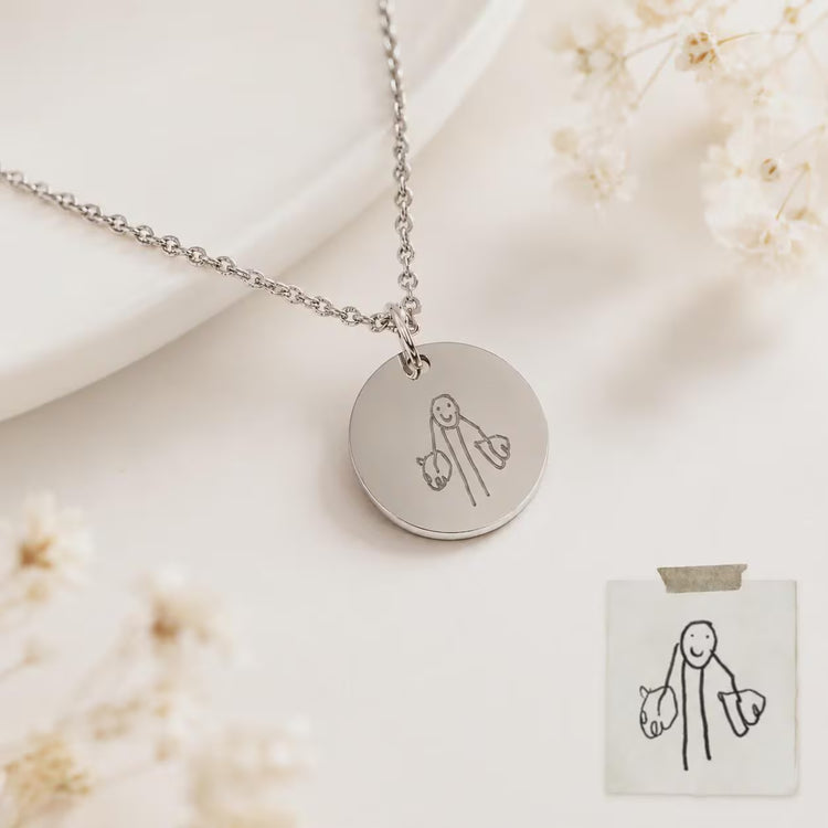 A silver round pendant necklace with engraved kid's drawing