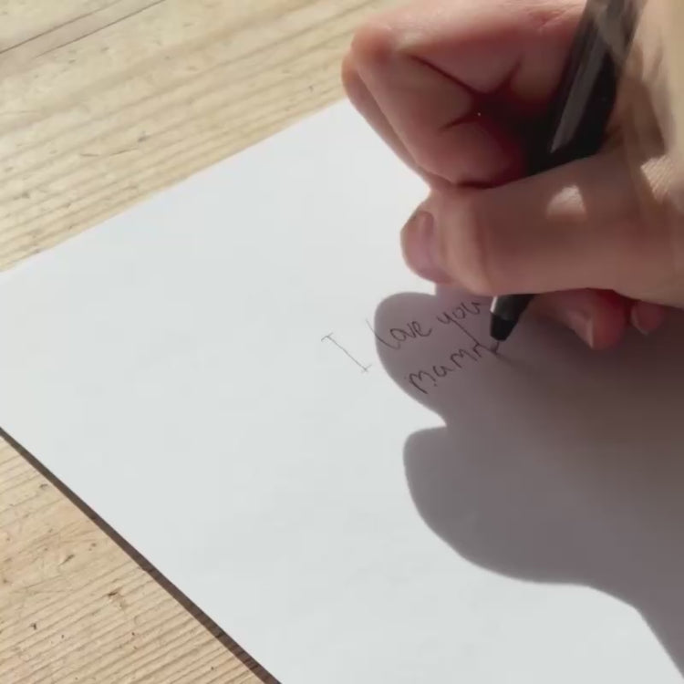 Hand writing a personal message on paper to be engraved onto a medallion necklace