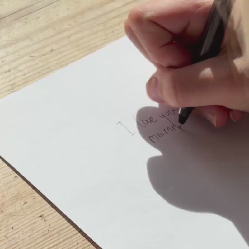 Hand writing a personal message on paper to be engraved onto a medallion necklace